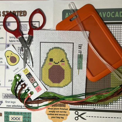 Avery the Avocado mini cross stitch DIY luggage tag kit with a orange bag tag, luggage tag attachment, Scissors, needle and thread, stamped Aida fabric, color instructions