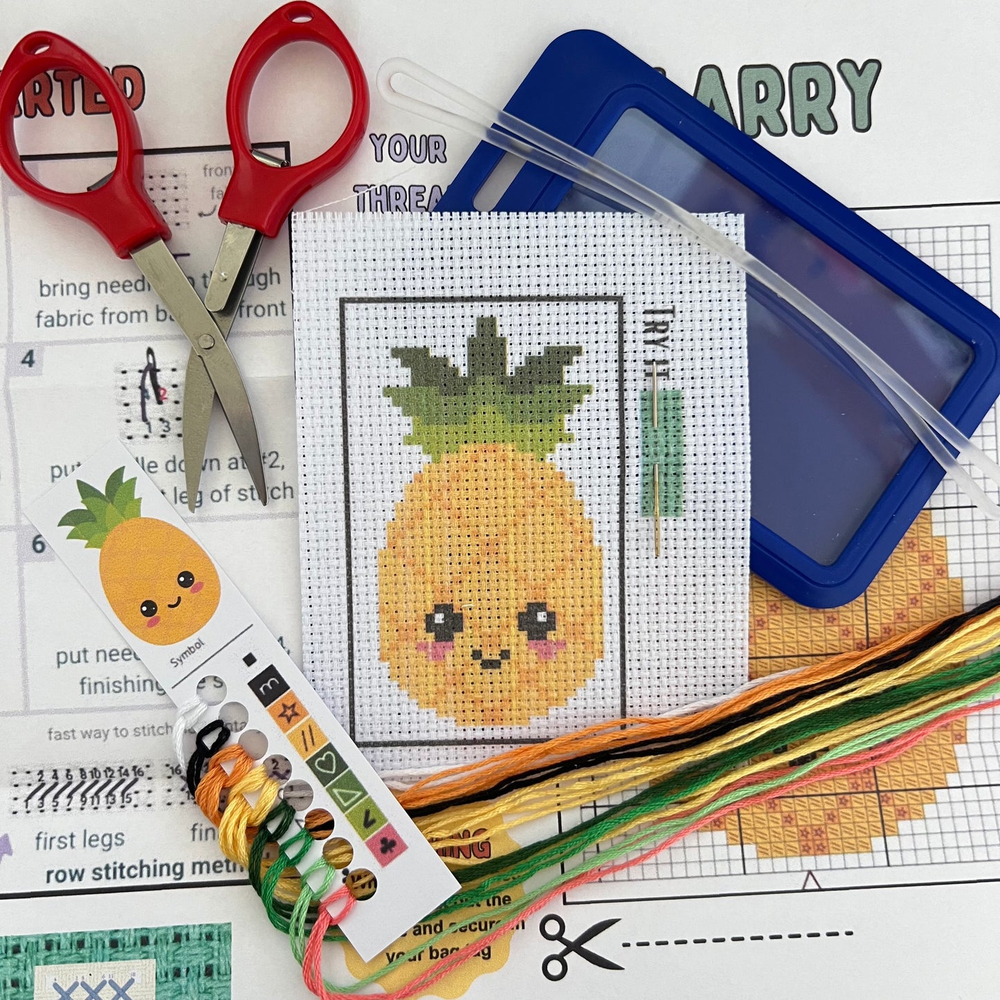 Larry the Pineapple mini cross stitch DIY luggage tag kit with a blue bag tag, luggage tag attachment, Scissors, needle and thread, stamped Aida fabric, color instructions