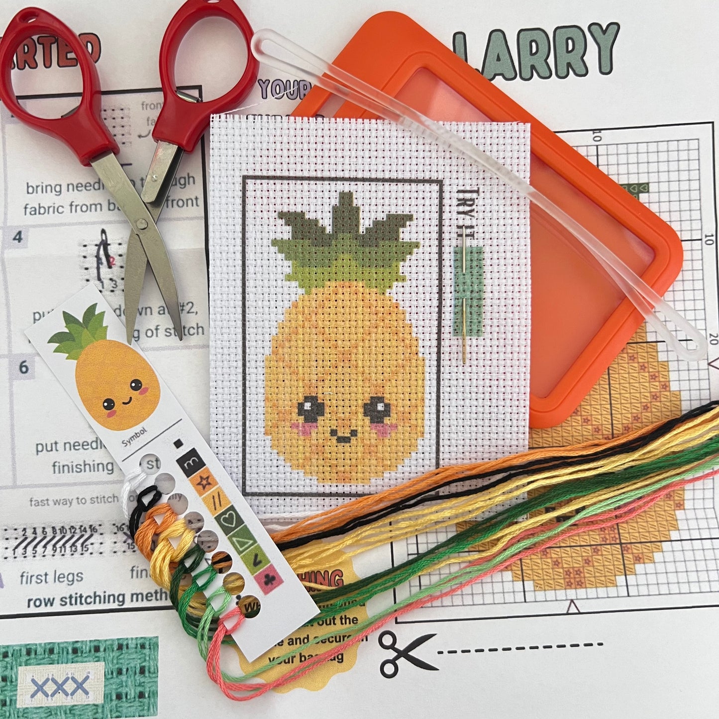 Larry the Pineapple mini cross stitch DIY luggage tag kit with a orange bag tag, luggage tag attachment, Scissors, needle and thread, stamped Aida fabric, color instructions