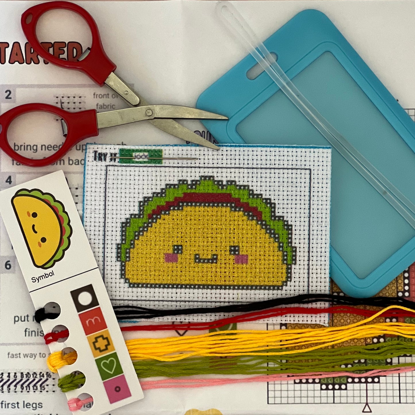 Timmy the Taco mini stamped cross stitch DIY luggage tag kit with a light blue bag tag, luggage tag attachment, Scissors, needle and thread, stamped Aida fabric, color instructions