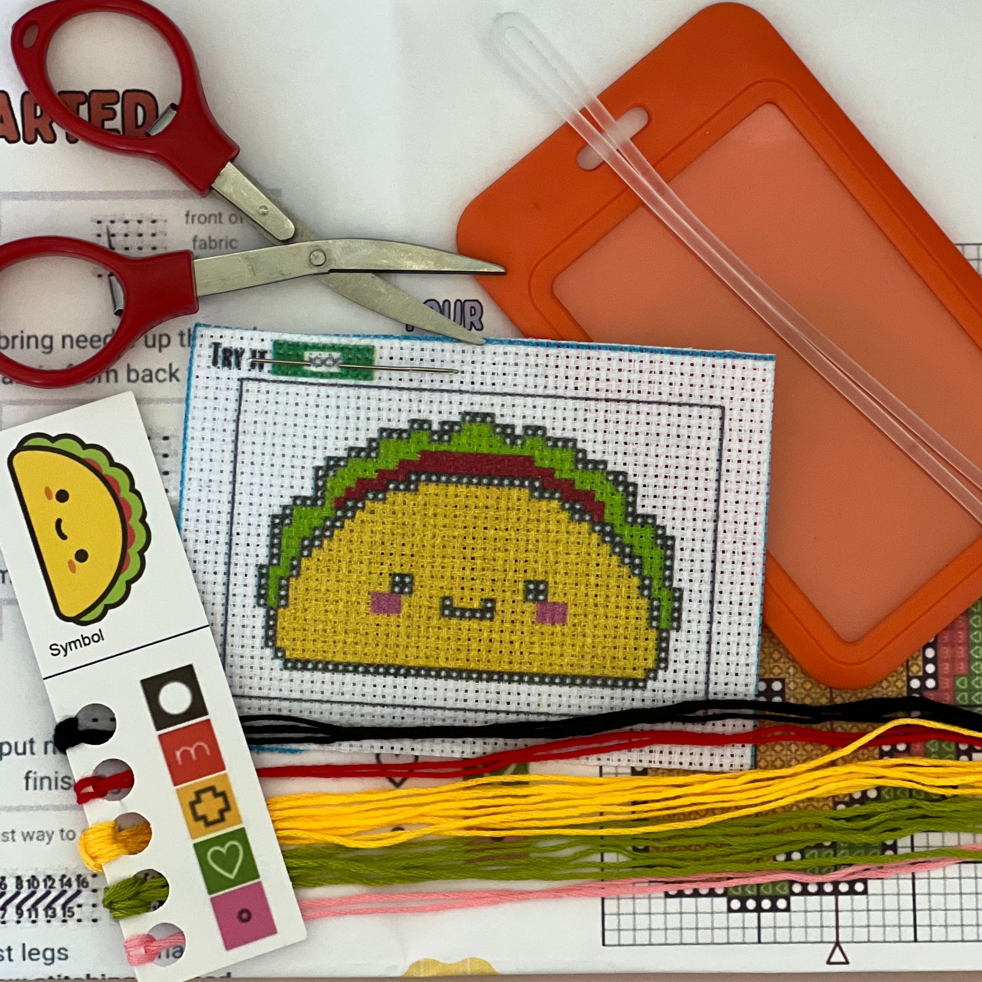 Timmy the Taco mini stamped cross stitch DIY luggage tag kit with a orange bag tag, luggage tag attachment, Scissors, needle and thread, stamped Aida fabric, color instructions